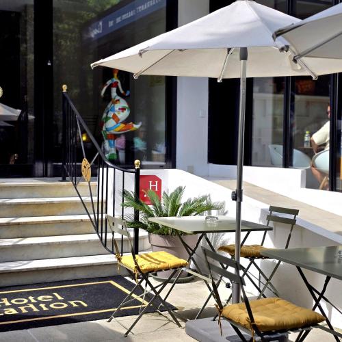 une table et des chaises avec un parasol sur le trottoir dans l'établissement Hotel Carlton Nice, Partially Renovated, à Nice