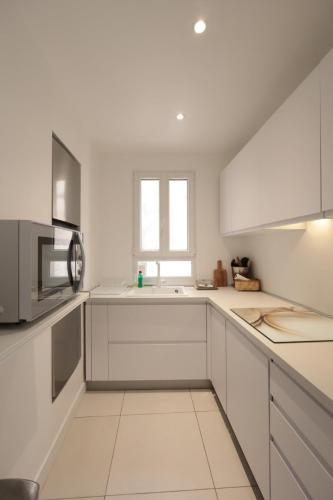 une cuisine blanche avec un évier et un micro-ondes dans l'établissement Le Nine - Apt 2 prs standing Vieil Antibes, à Antibes