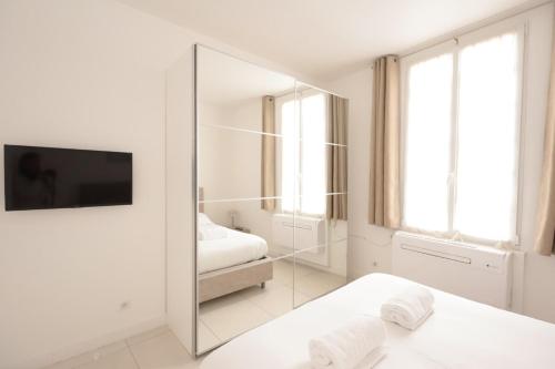 - une chambre blanche avec un miroir et 2 lits dans l'établissement Le Nine - Apt 2 prs standing Vieil Antibes, à Antibes