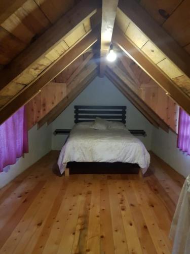 a bedroom with a bed in a loft with wooden floors at Cabañas los Cedros in Santiago Oxtempan