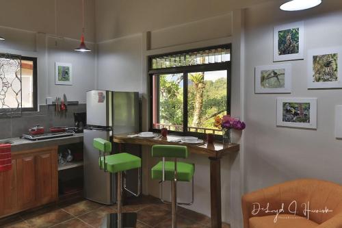 Una cocina con refrigerador y una mesa con taburetes verdes. en Laughing Falcon Studio, en El Castillo de La Fortuna
