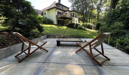 two wooden chairs sitting on a patio with a house at PepperLake in Overijse