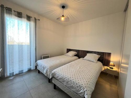 une chambre avec deux lits et une fenêtre dans l'établissement Naïa Lab, à Sérignan