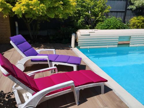 a group of purple and white lounge chairs next to a swimming pool at Charmants studios "Le Nid de Lou" et "Le Cocon de Théo" à Rosheim in Rosheim