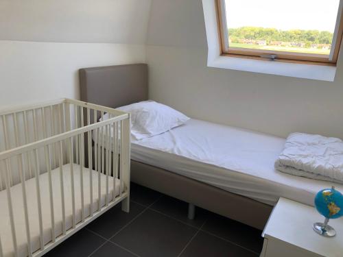 a small bedroom with a crib and a window at Vakantiehuis De Panne in De Panne