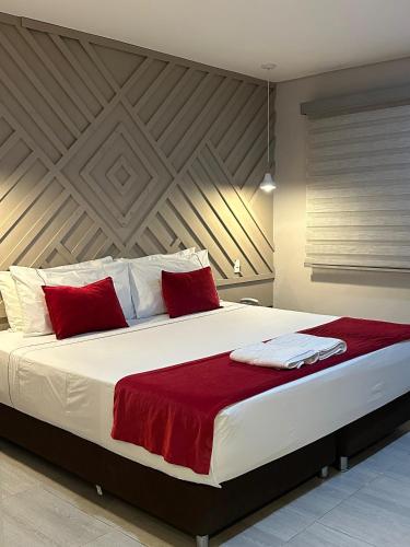 a bedroom with a large white bed with red pillows at Hotel Santa Clara Boutique in Montería