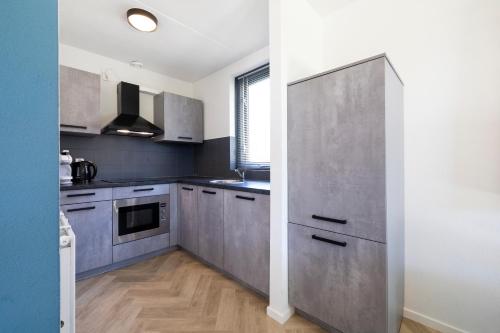 a kitchen with gray cabinets and a large refrigerator at Holiday home for the whole family in Ewijk