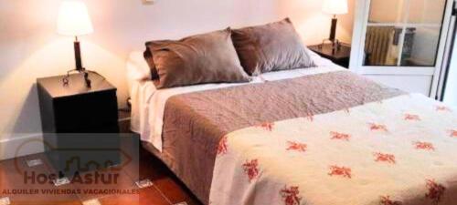 a bedroom with a bed and two lamps and a window at Guirigay CASA CON PISCINA in Muros de Nalón