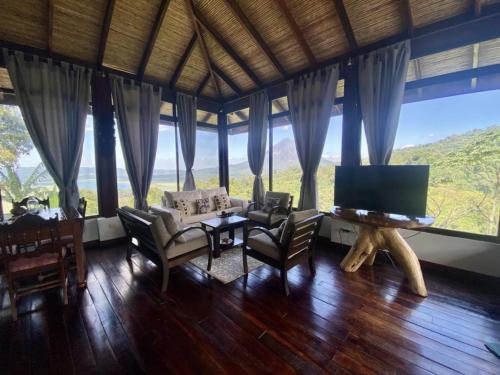 a living room with a tv and a table and chairs at Arenal Birdsong, Entire Villa W- Stunning Views,! in El Castillo de La Fortuna