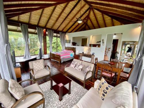 a living room with white furniture and a bedroom at Arenal Birdsong, Entire Villa W- Stunning Views,! in El Castillo de La Fortuna