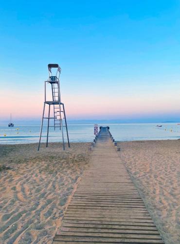 une tour de sauvetage sur une plage avec un chemin en bois dans l'établissement Villa de luxe, piscine, plage 7mns, St Tropez 15km, à La Croix-Valmer