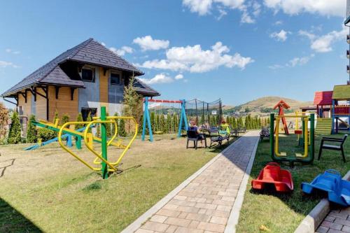 a playground with slides and play equipment in a yard at Apartman Tajmles Wellnes & Spa in Zlatibor