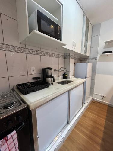 a white kitchen with a stove and a sink at 5 min da Praia! 2 Quartos Copacabana in Rio de Janeiro