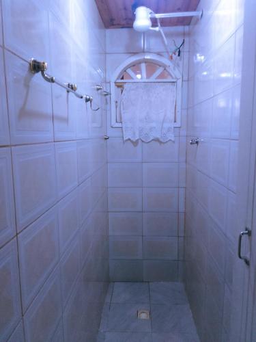 a white tiled shower with a towel hanging from a window at Suítes Lar Doce Lar in Lavras Novas