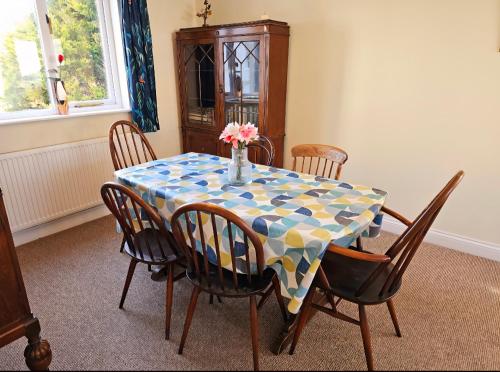 a table with chairs and a vase with flowers on it at Relaxing coastal getaway in Mortehoe, Woolacombe in Mortehoe