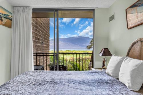 a bedroom with a bed and a balcony with a view at Kauhale Makai 230 in Kihei