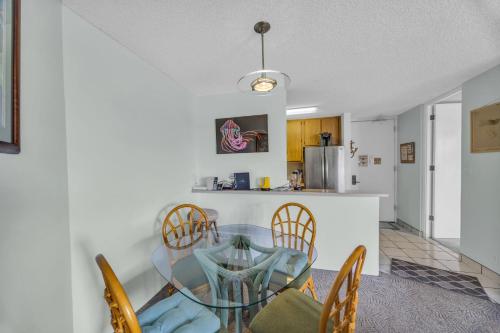 a dining room and kitchen with a glass table and chairs at Kauhale Makai 230 in Kihei