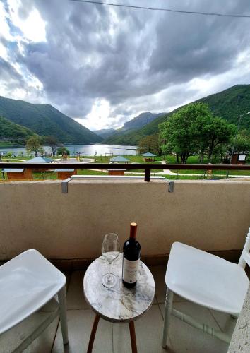 a table with a bottle of wine and two chairs at Apartment Lake story in Pluzine