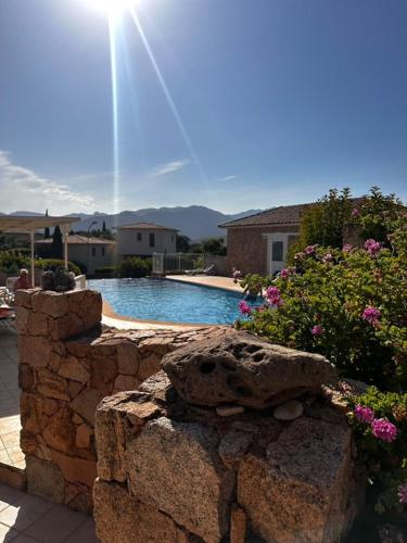 un mur en pierre à côté d'une piscine dans l'établissement Residence Marina Di A Testa, à Sainte-Lucie de Porto-Vecchio