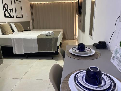 a room with a bed and two tables with plates on it at Manaíra Apart Hotel in João Pessoa