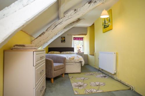 a attic bedroom with a bed and a chair at Rhostwarch Old Farmhouse Newport, Pembrokeshire in Eglwyswrw