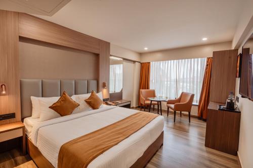 a hotel room with a large bed and a table at Classik Fort Inn & Suites in Cochin