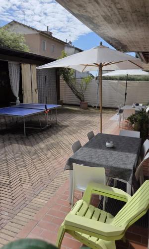 a ping pong table and chairs with an umbrella on a patio at Itaca in Lido di Fermo