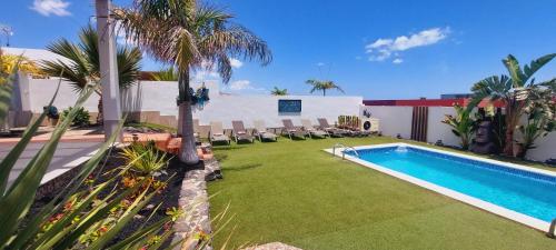 a backyard with a swimming pool and a lawn with chairs at Villa Del Corazon Salinas Golf in Caleta De Fuste