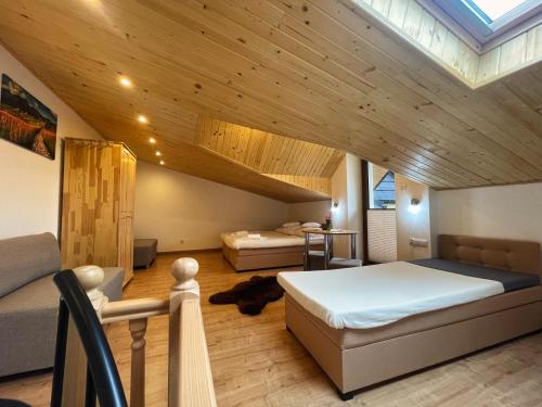 a bedroom with two beds in a room with wooden ceilings at Apartamenty QUER SPA Jacuzzi i Sauna in Bańska Niżna