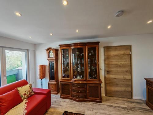 a living room with a wooden cabinet and a red couch at VipStay - Stilvoll und geräumige Apartments mit Terasse oder Balkon, Küche, kostenloses Parken, WLAN, Smart Tv in Wiesloch