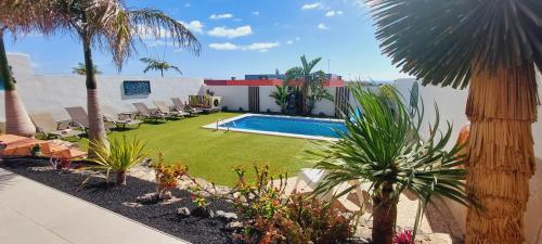 a backyard with a swimming pool and palm trees at Villa Del Corazon Salinas Golf in Caleta De Fuste