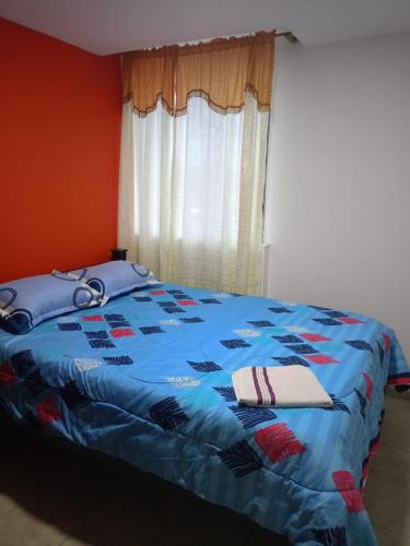 a bed with a blue comforter with towels on it at Ipiales puerta de oro in Ipiales
