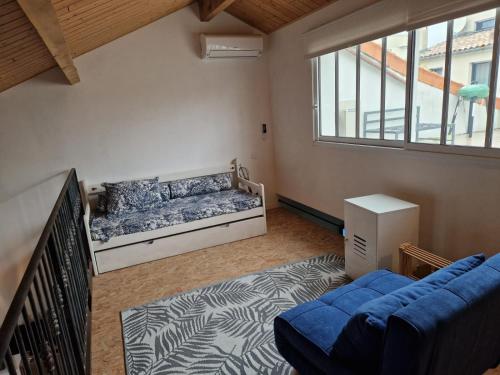 un salon avec un canapé bleu et une fenêtre dans l'établissement Authentique maison de pêcheur, au Grau-du-Roi