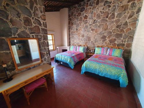 a bedroom with two beds and a mirror and a stone wall at Sandy Shores Cabaña 6A in La Paz