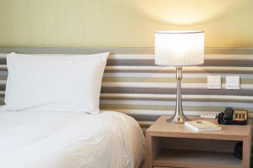 a bedroom with a bed and a lamp on a table at 塔木德酒店 台中火車站館 Talmud Hotel Taichung Station in Taichung