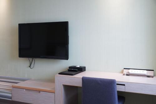 a room with a desk with a tv on the wall at 塔木德酒店 台中火車站館 Talmud Hotel Taichung Station in Taichung