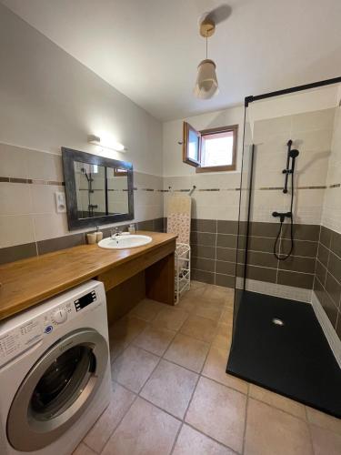 une salle de bain avec une machine à laver et un lavabo dans l'établissement T2 vue sur le parc de la vanoise, à Champagny-en-Vanoise