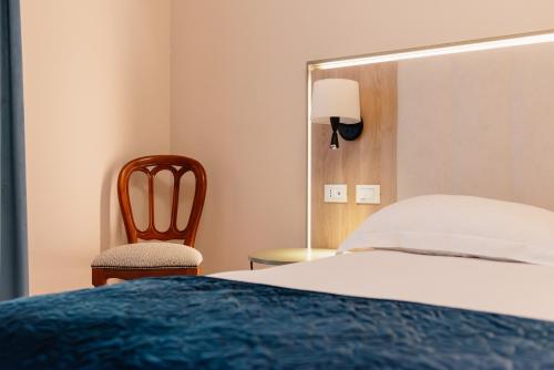 a bedroom with a bed and a chair and a mirror at Hotel Due Palme in Mergozzo