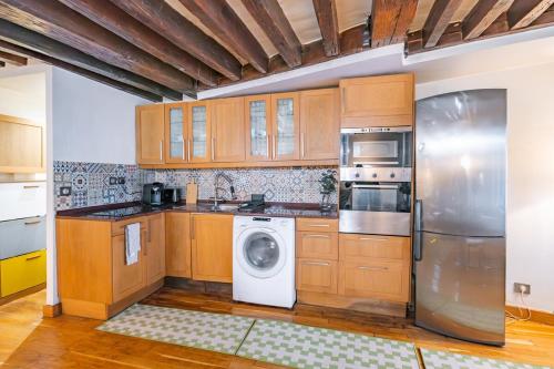 une cuisine avec des armoires en bois et une laveuse et une sécheuse dans l'établissement Apt Grands Boulevards 4 Guests, à Paris