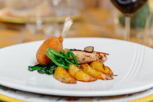 a white plate with meat and vegetables on a table at Hotel Due Palme in Mergozzo