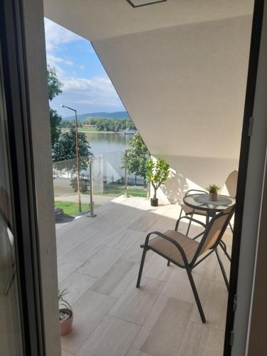 a table and a chair on a balcony with a view of a lake at Duna-Part Deluxe in Vác