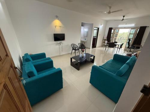 a living room with two blue couches and a tv at Hope in Udupi