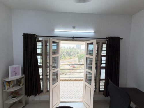 a room with a door with a window with a view at Hope in Udupi