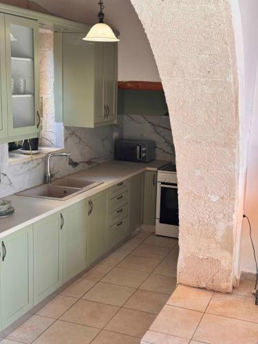 a kitchen with green cabinets and a stone wall at Skandalis Apartments with pool in Chorafakia