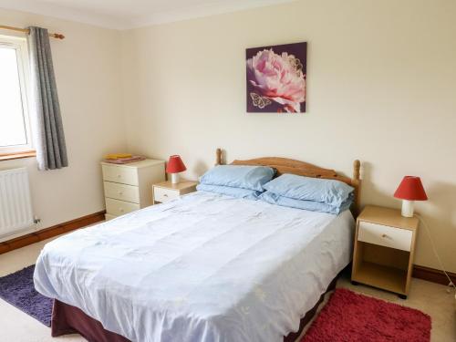 a bedroom with a large white bed with two lamps at Awel Y Ddol in Amlwch