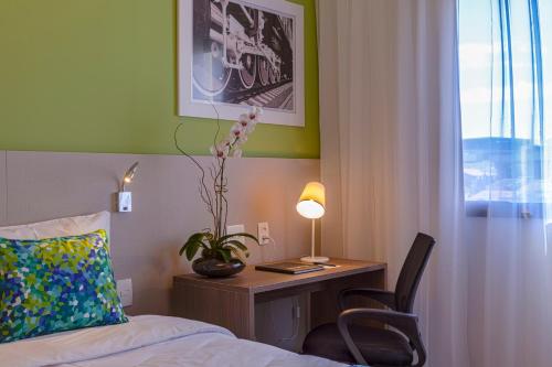 a hotel room with a bed and a desk with a lamp at Blue Tree Towers Valinhos in Valinhos