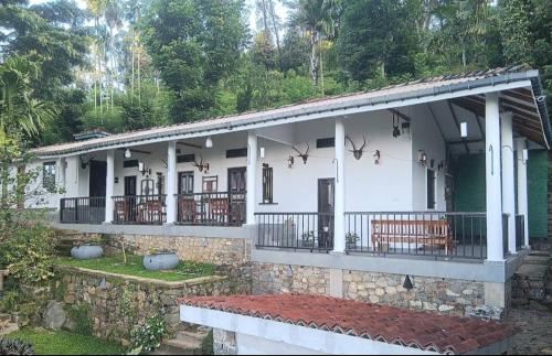 ein weißes Haus mit einer Steinmauer in der Unterkunft Beragala Estate and Resort in Haputale