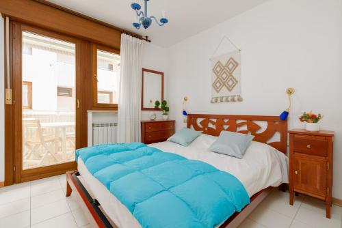 a bedroom with a large bed with blue sheets at L'Angolo Fiorito con terrazza e in pieno centro in Grado