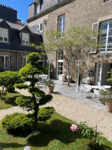 a garden with a pine tree in front of a building at Hôtel Victor Hugo in Pontorson