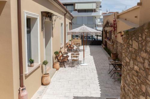 an outdoor patio with chairs and tables and an umbrella at Strofilia House Near ATH Airport in Markopoulo